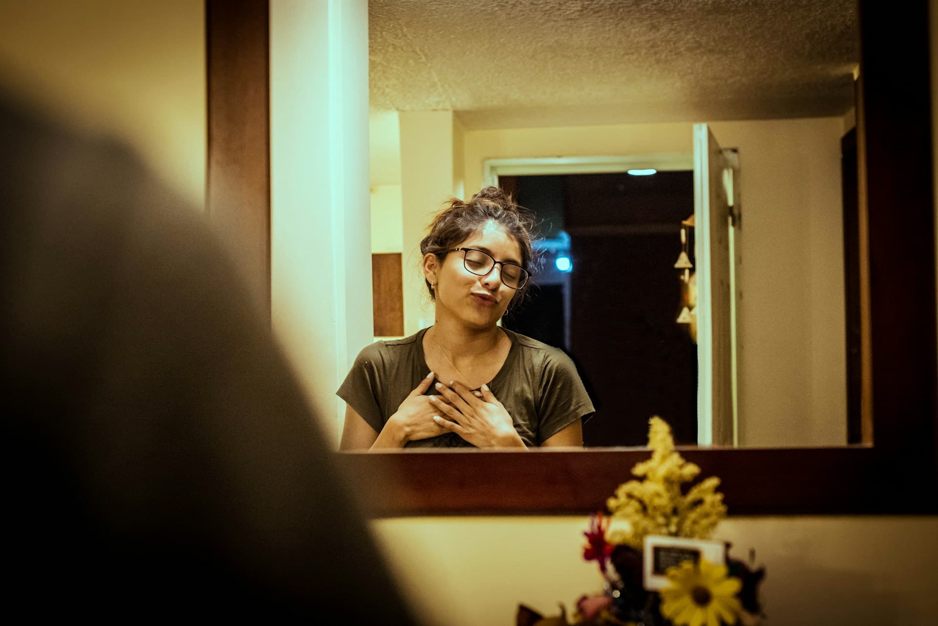 Person practicing a speech in front of a mirror at home, using gestures and facial expressions for rehearsal.